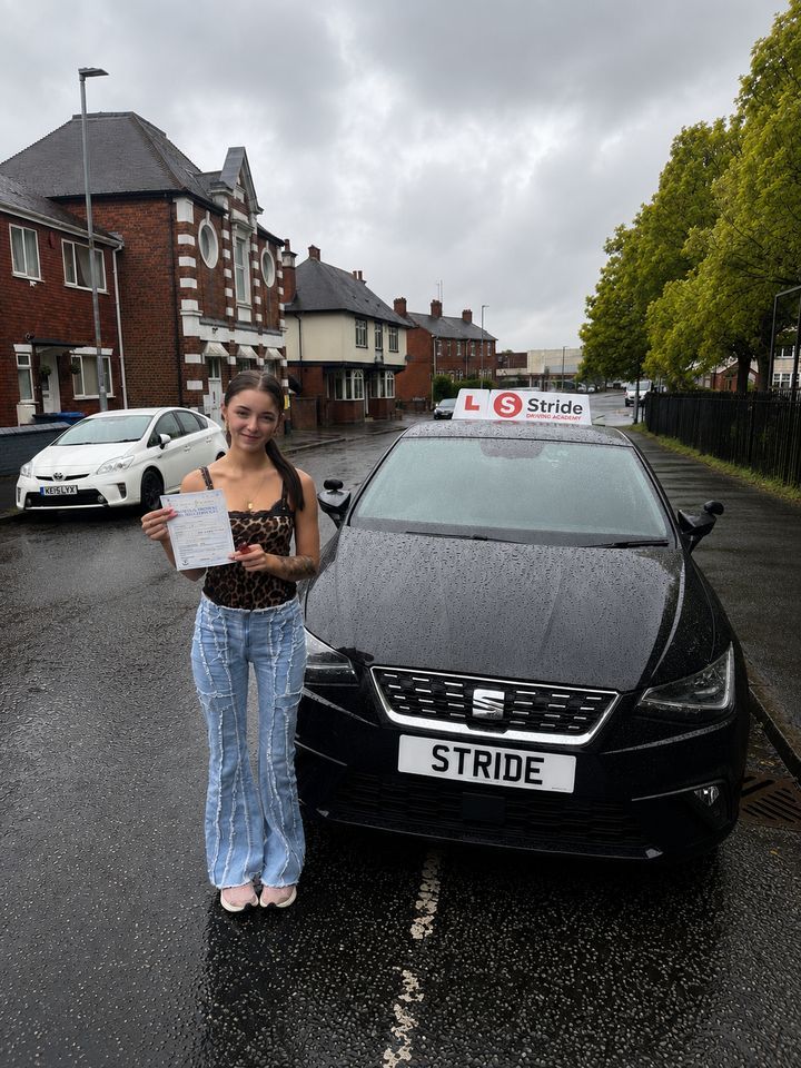 A Stride pupil with their practical driving test pass certificate beside the Stride car