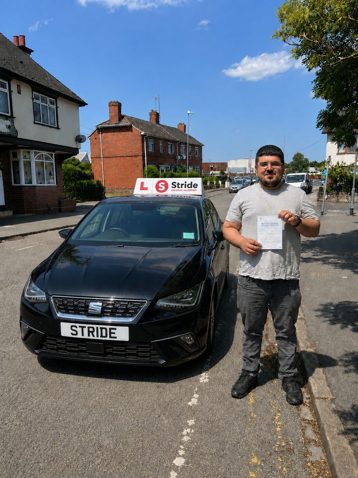 A Stride pupil with their practical driving test pass certificate beside the Stride car