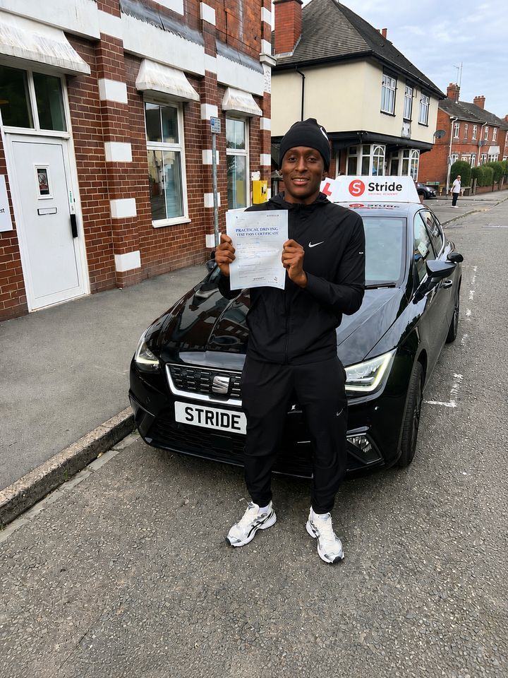 A Stride pupil with their practical driving test pass certificate beside the Stride car