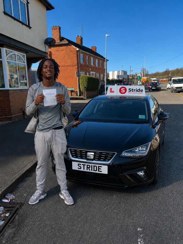 A Stride pupil with their practical driving test pass certificate beside the Stride car