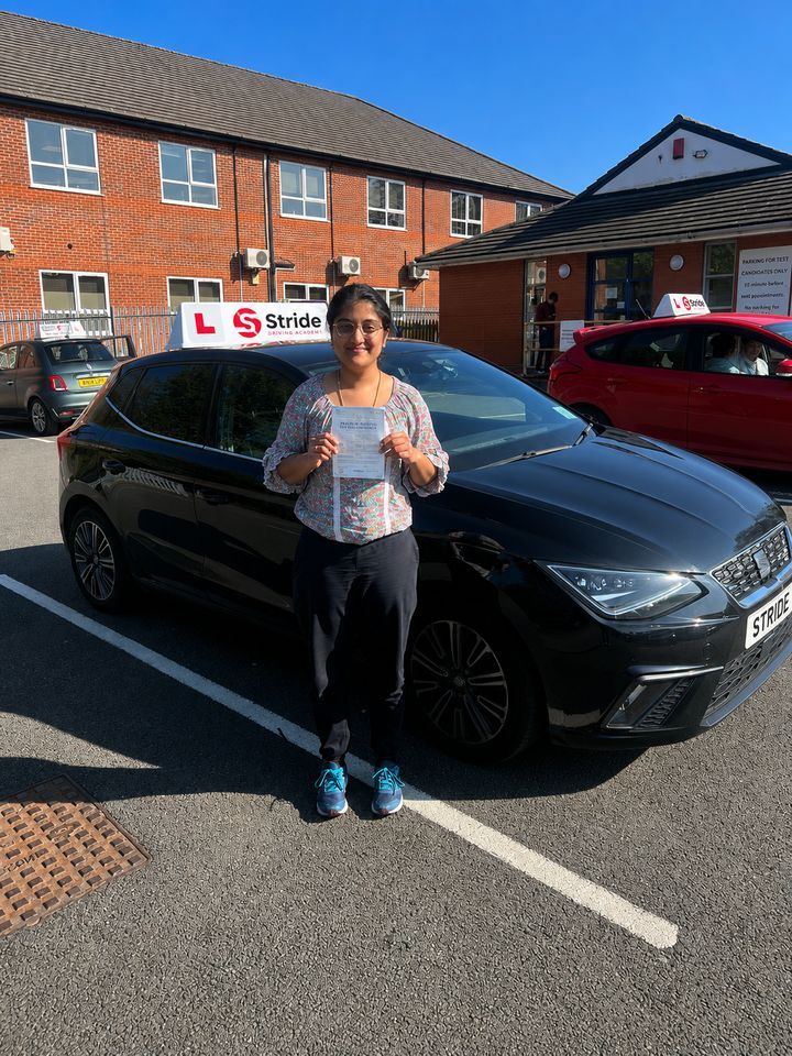 A Stride pupil with their practical driving test pass certificate beside the Stride car