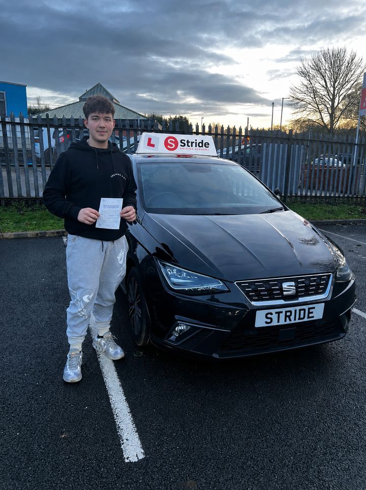 A Stride pupil with their practical driving test pass certificate beside the Stride car