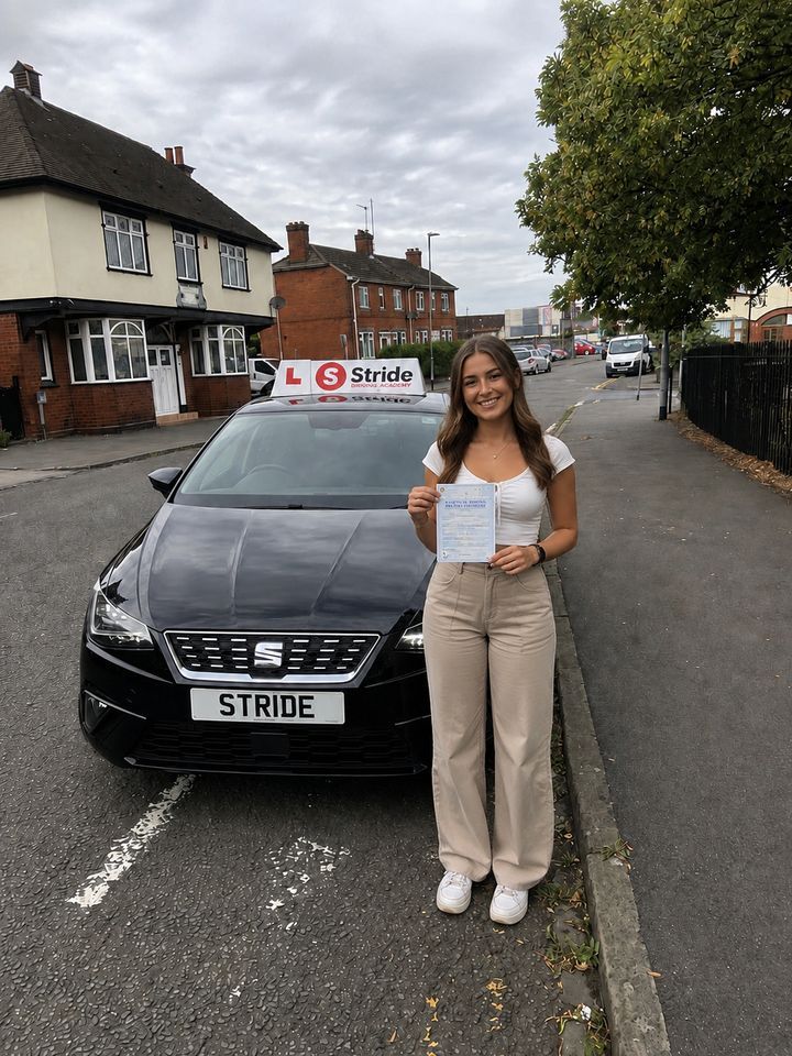 A Stride pupil with their practical driving test pass certificate beside the Stride car