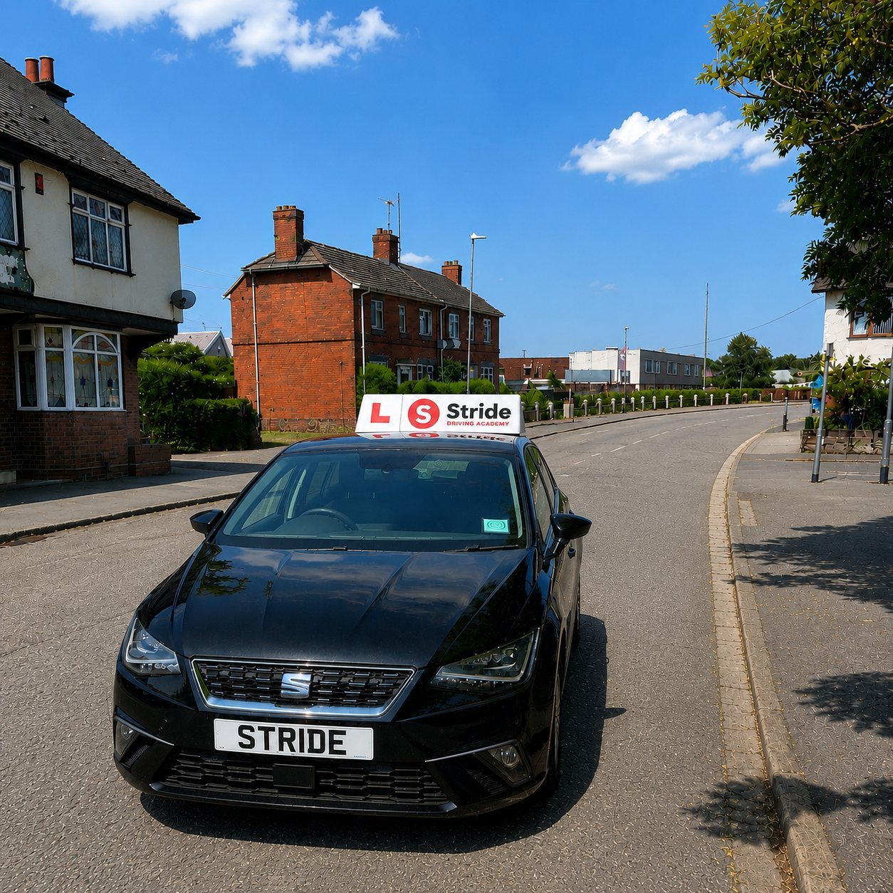 A modern silver learner car with an L plate, parked on a red-brick terraced street at dusk.